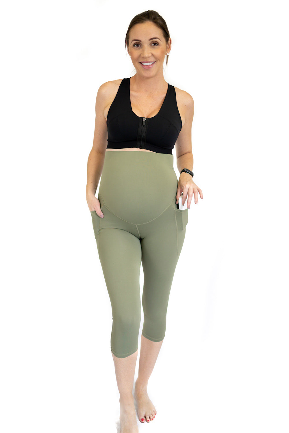 Pregnant woman in black top and olive green maternity leggings showcasing comfort and style