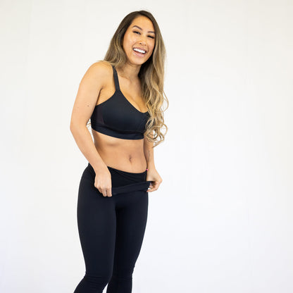 Woman in black workout attire smiling, showcasing 7/8 Body Shapewear Leggings with pockets