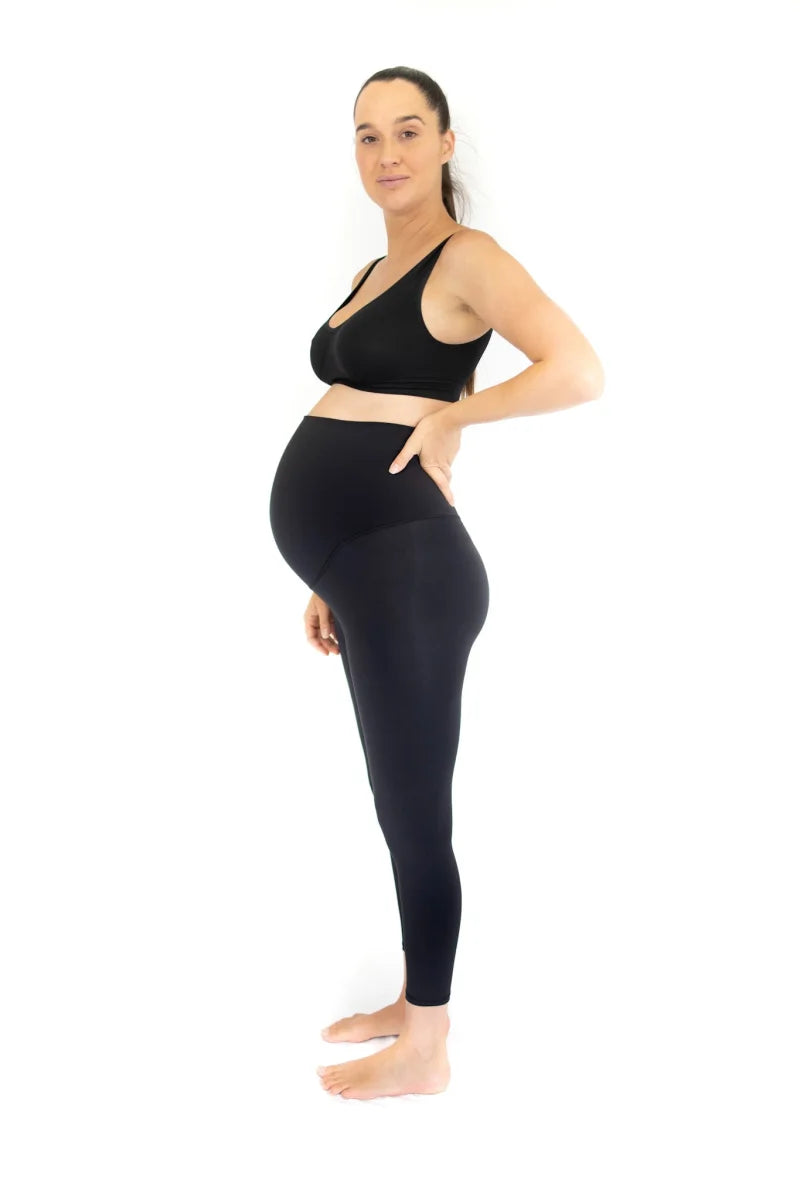 Pregnant woman in black workout attire wearing Emamaco maternity leggings in profile