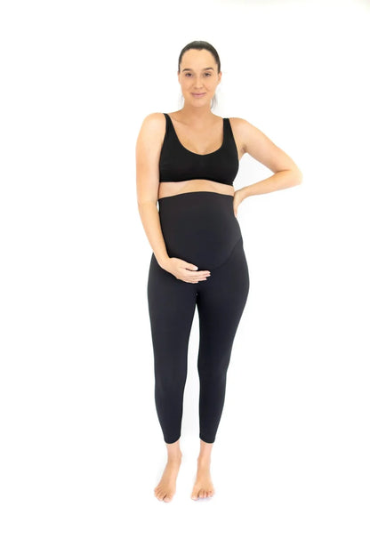 Pregnant woman in black Emamaco maternity leggings standing confidently with hand on hip