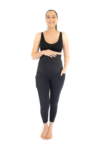 Woman in dark athletic wear showcasing Emamaco maternity leggings with pockets