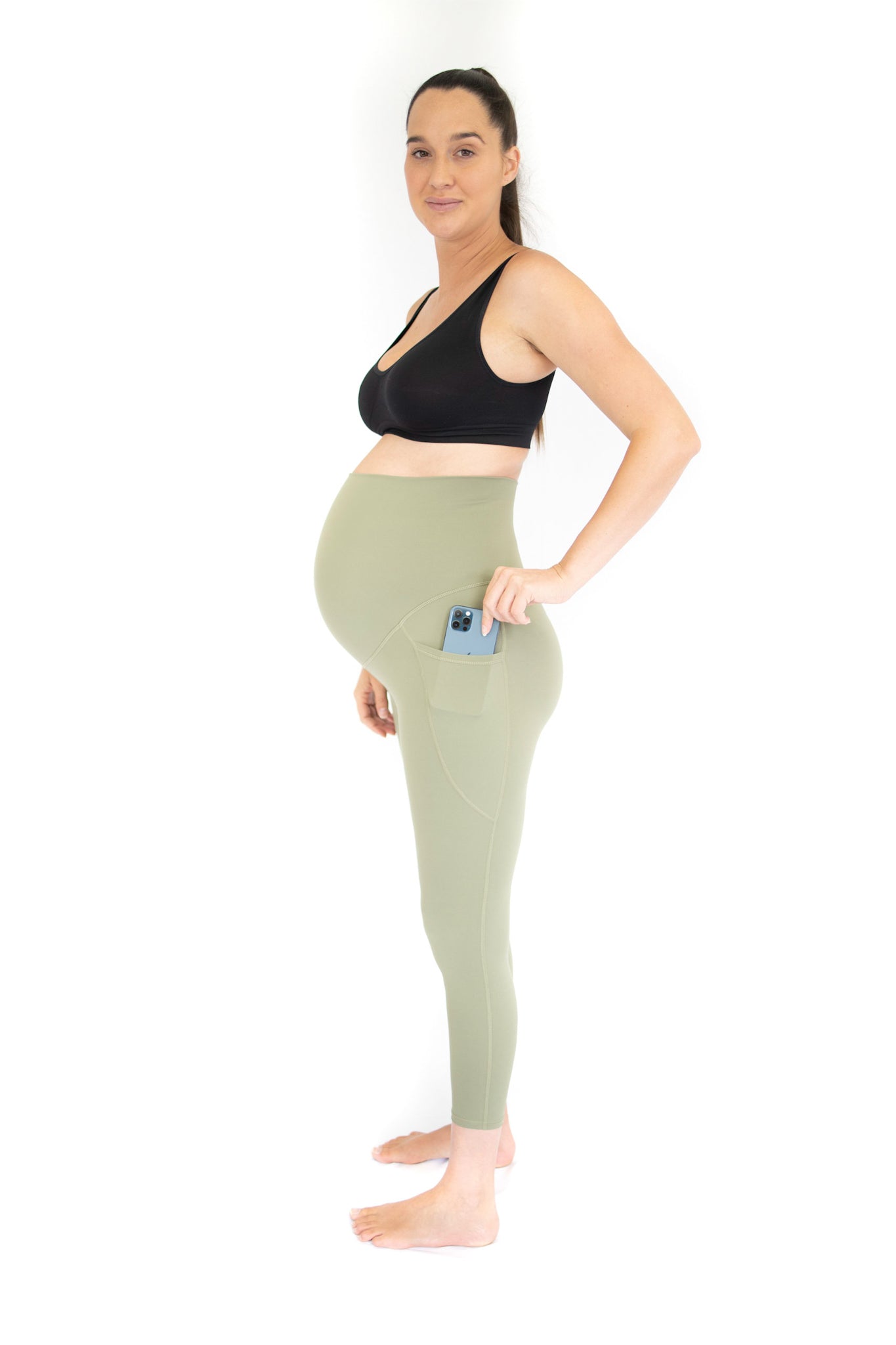 Pregnant woman in black sports bra and light green emamaco maternity leggings