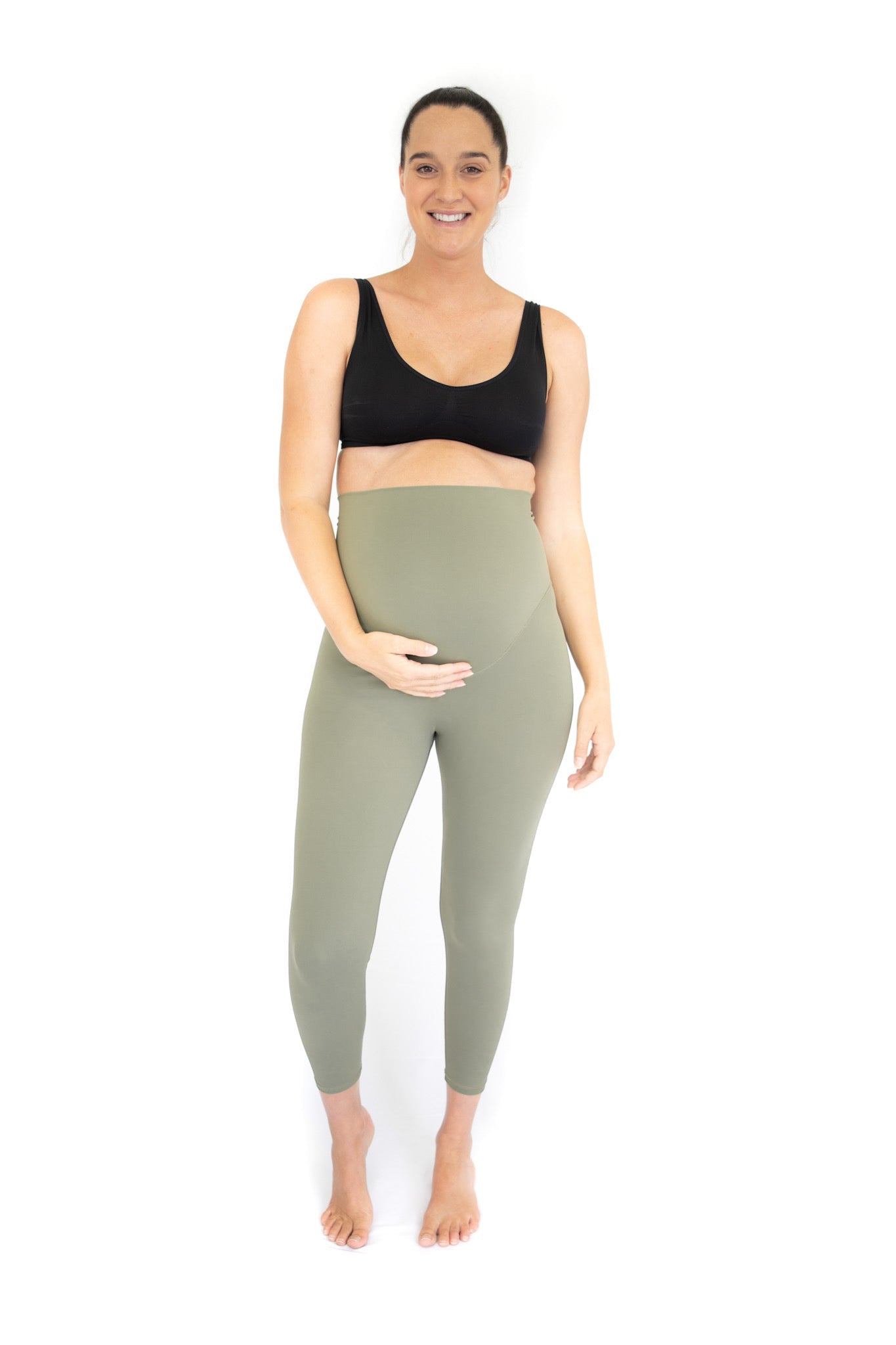 Pregnant woman in black sports bra and sage green maternity leggings by Emamaco Maternity