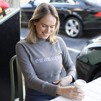 Woman in a crisp charcoal grey sweatshirt featuring emamaco design