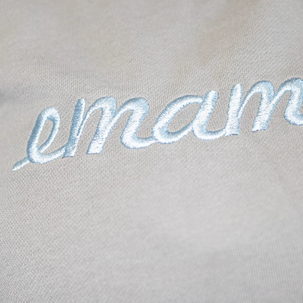 Embroidered cursive text emam on light fabric of cropped sweat maternity activewear