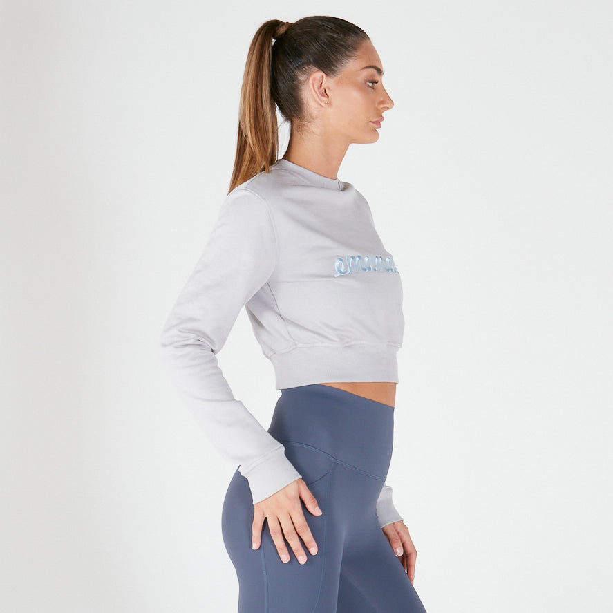 Woman in white cropped sweat and blue leggings, showcasing stylish maternity activewear