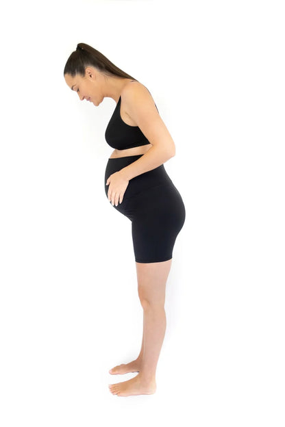 Woman in black emama Maternity Bike Shorts standing sideways, perfect for pregnant life