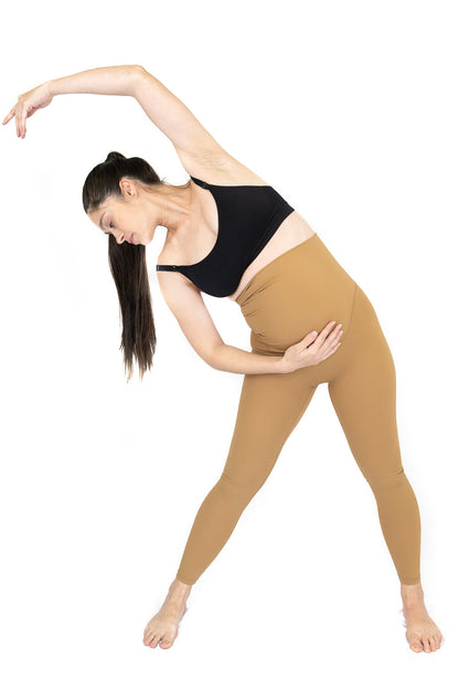 Woman in athletic wear performing side bend yoga pose in Emama Maternity Leggings