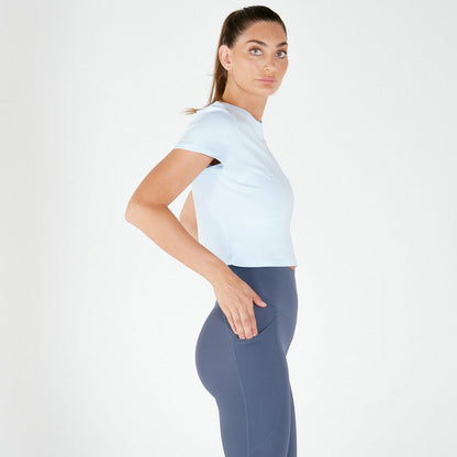 Woman in loose fitting Emamaco light blue tee and navy blue leggings, posing sideways