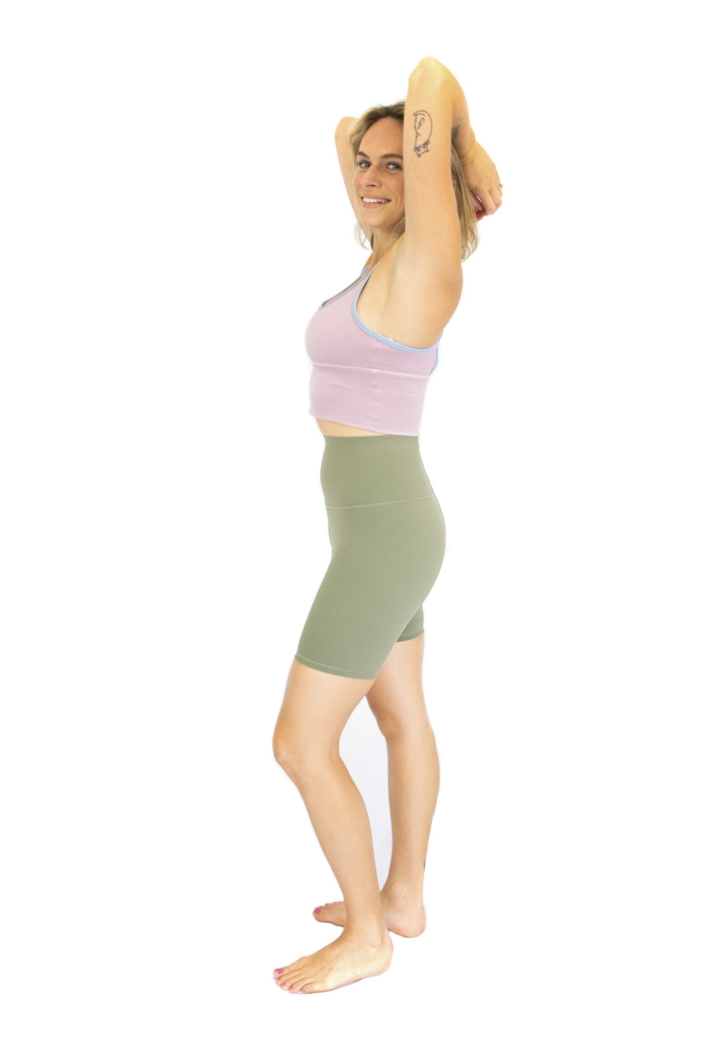 Woman in exercise attire stretching, showcasing Shaper Move Shorts - Olive, final sale