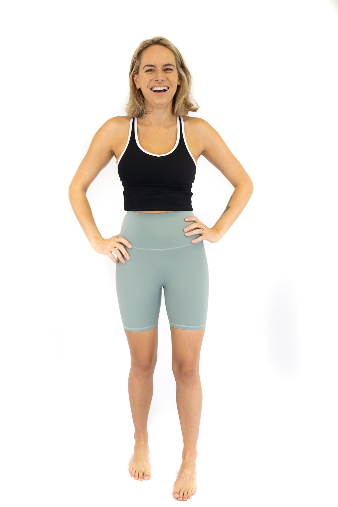 Woman in athletic wear smiling while showcasing Shaper Move Shorts in Spearmint - Final Sale