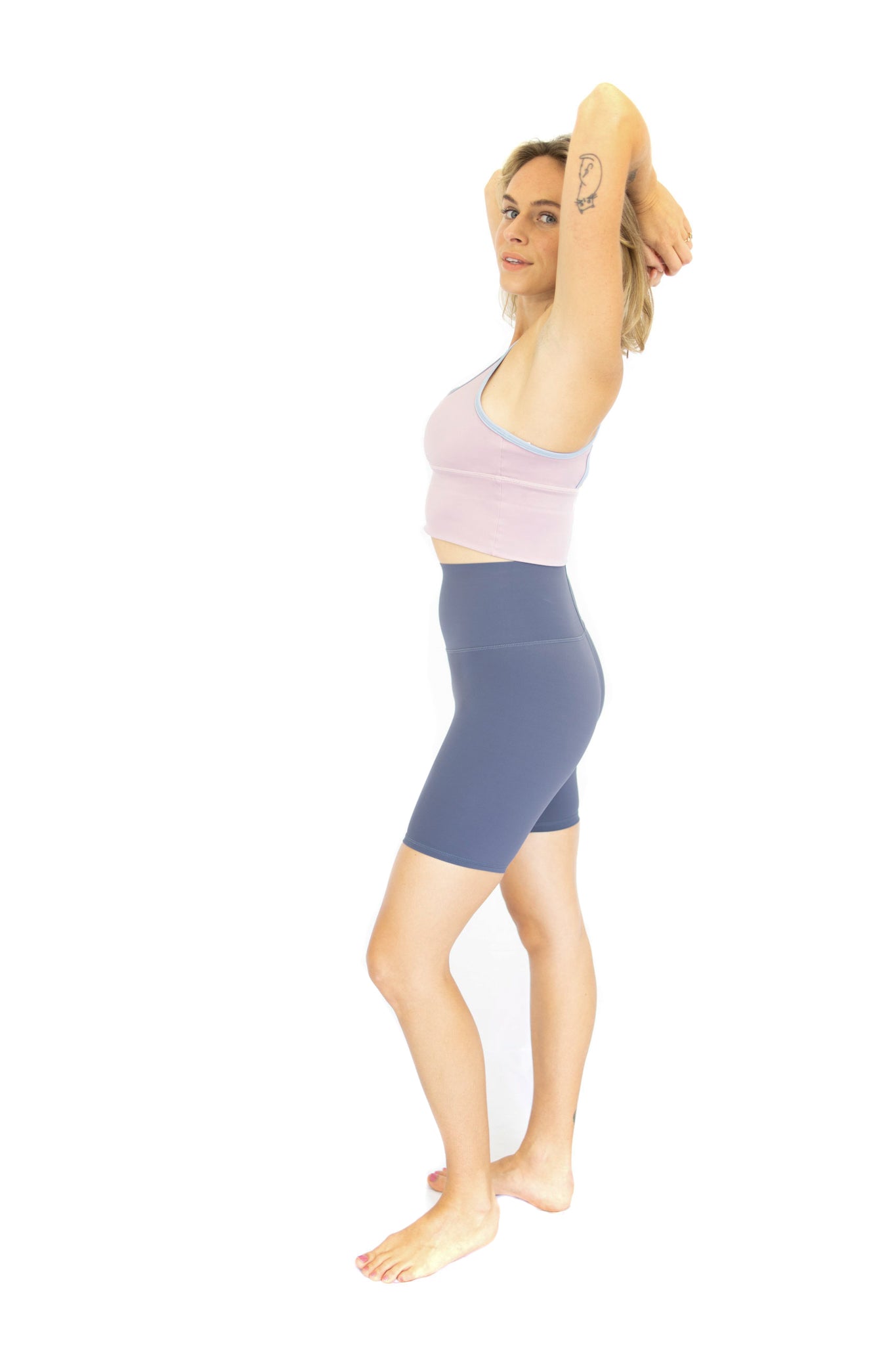 Woman in workout attire stretching with arms raised in Shaper Move Shorts final sale