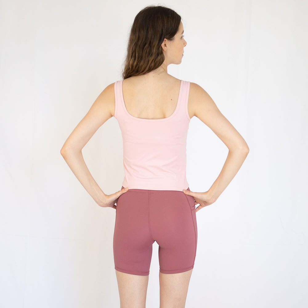 Woman in pink tank top and mauve shorts, perfect for Emamaco Everyday at yoga studio