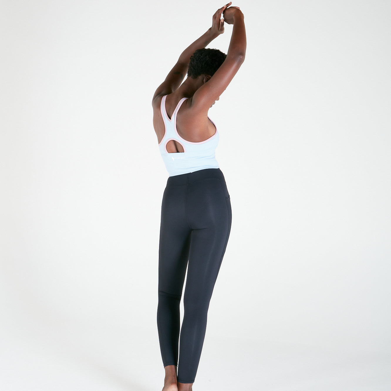 Woman in athletic wear stretching arms, showcasing Vibe Leggings with regular fit waistband