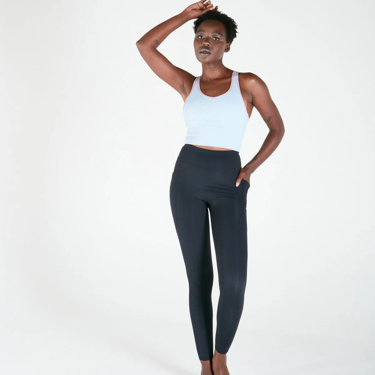 Woman in white tank top and dark leggings showcasing Vibe Leggings with regular fit